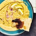 Bowl of Greek fava dip topped with olive oil, lemon, and red onion