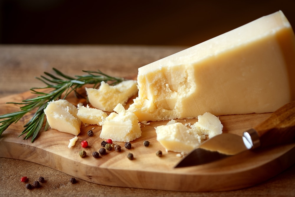 Parmigiano,Reggiano,Cheese,Portion,With,Crumbs,On,Cutting,Board.,Ortion