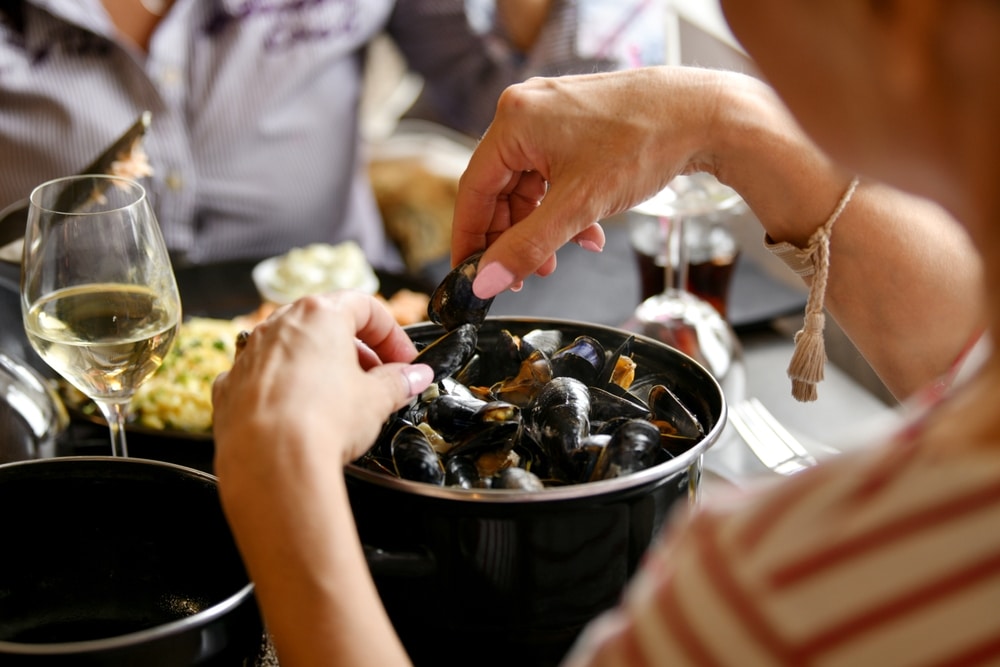 Woman's,Hands,Holding,Mussels,Over,A,Pan,Of,Mussels,In
