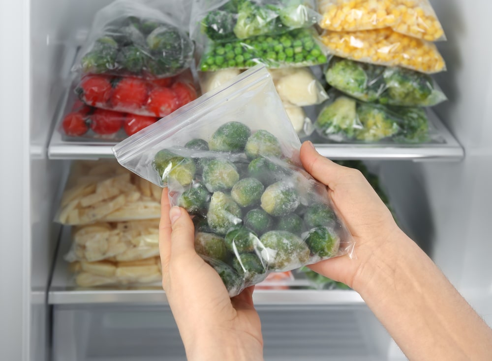 Woman,Holding,Plastic,Bag,With,Frozen,Brussels,Sprouts,Near,Open