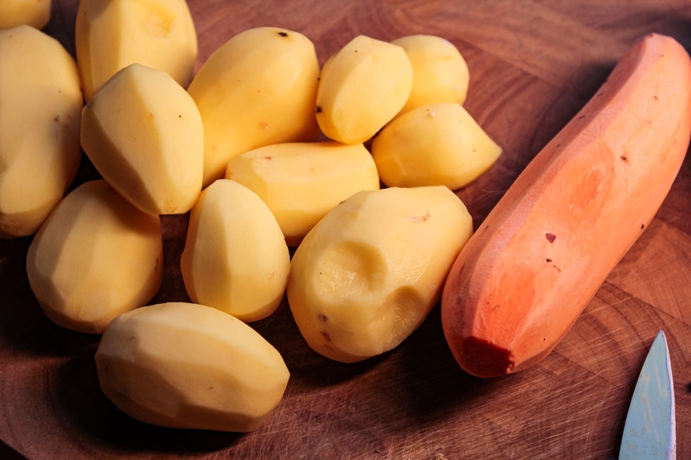 Peeled,Sweet,Potatoes,And,Regular,Potatoes,On,A,Wooden,Cutting